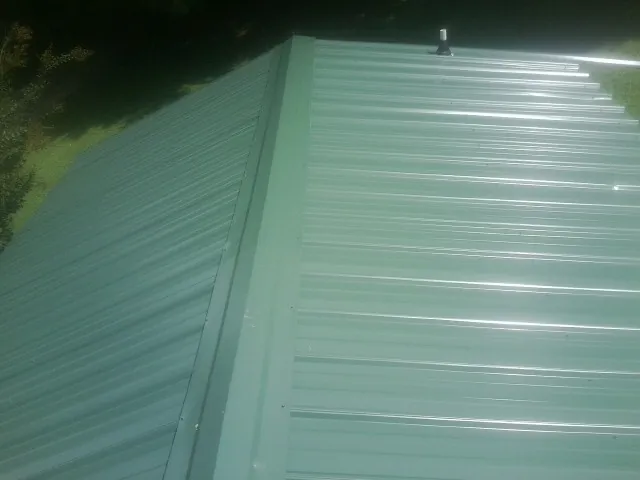 New green metal panels meeting at the ridge of a roof — Flat Roof Repair work by our crew in Wycombe
