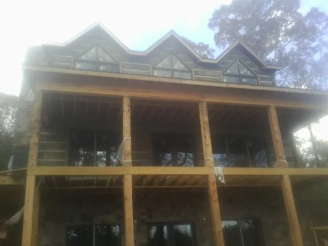 Dormers and porch framing on a large log home under construction — Roof Coating work by our crew in Wycombe