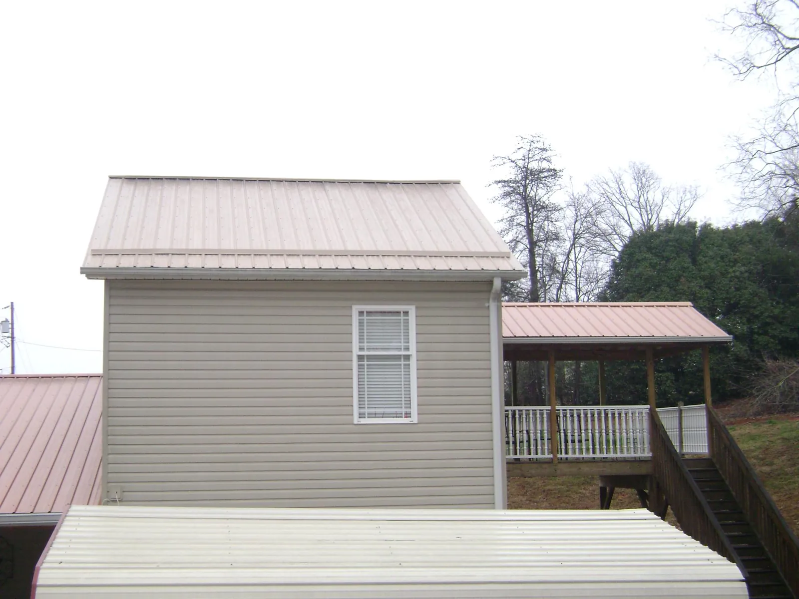 Tan metal roofs on a two story addition and attached porch, from a Roof Replacement job in Wycombe