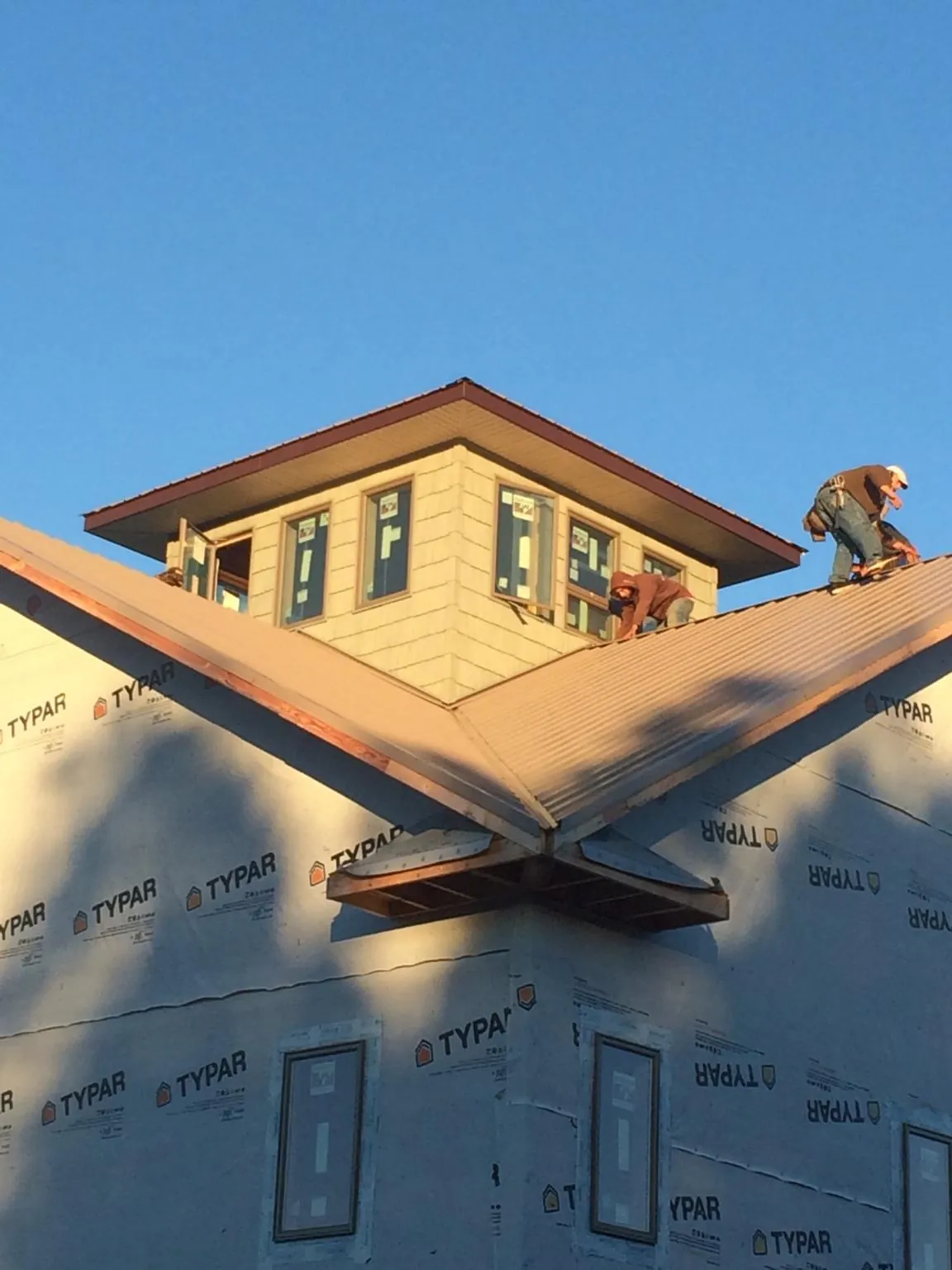 Roofers working around a rooftop cupola on a new metal roof at sunset — Roof Waterproofing in Wycombe by Roofing Brothers